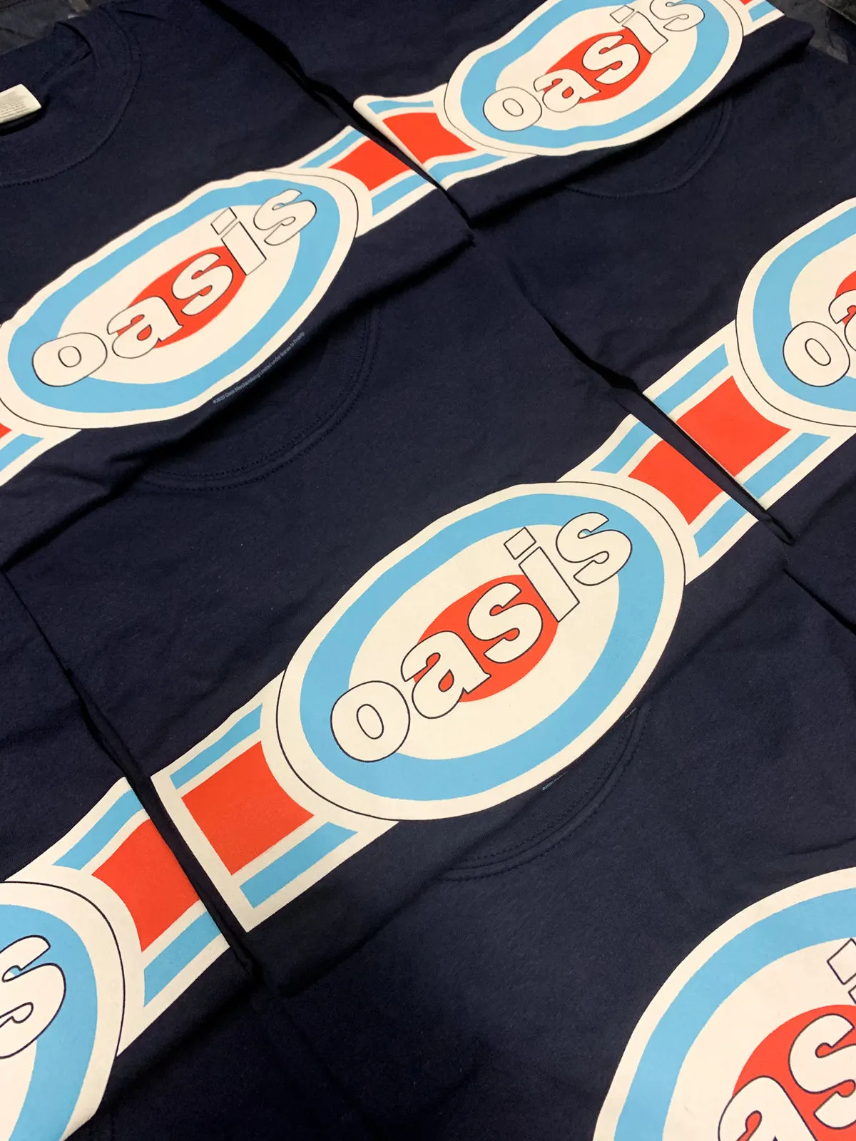Rows of navy Oasis t-shirts printed with the 1996 oblong target logo